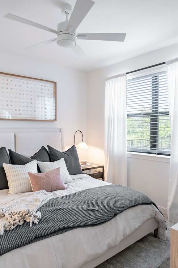 A bedroom with a bed, nightstand, and a plant.