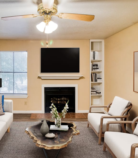 a living room with couches and chairs and a tv above a fireplace at Village Oaks Apartments, Austin, Texas