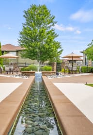 a fountain in the middle of a yard with a house in the background at Avignon Apartment Homes, Olathe, KS
