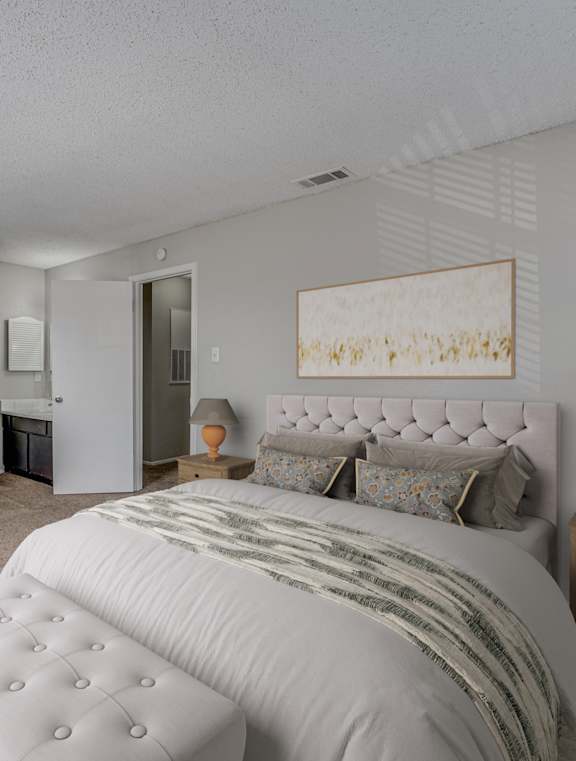 A bedroom with a large bed, a dresser, and a nightstand with a lamp.