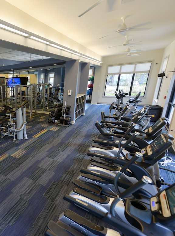 A gym with a variety of equipment including treadmills, weights, and exercise machines.