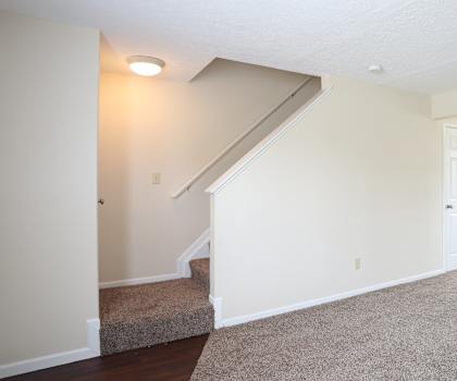 A spacious room with a staircase leading to the second floor.