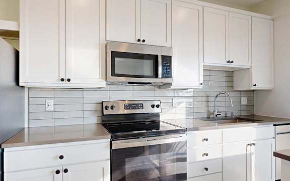 A kitchen with white cabinets and appliances.
