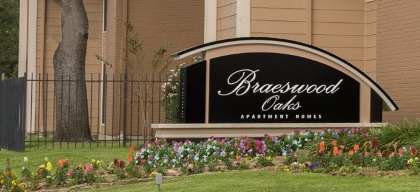 a large tan building with a black and red sign in front of it