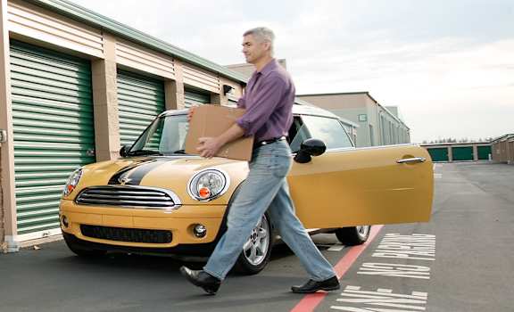 A man carrying boxes is entering a storage facility.