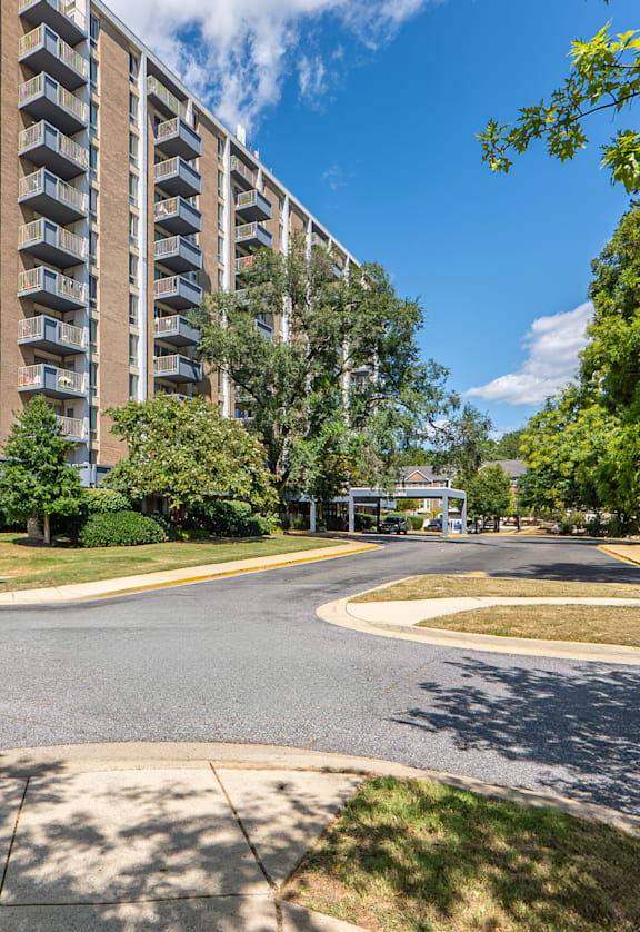 A tall apartment building with a blue sky and clouds in the background.