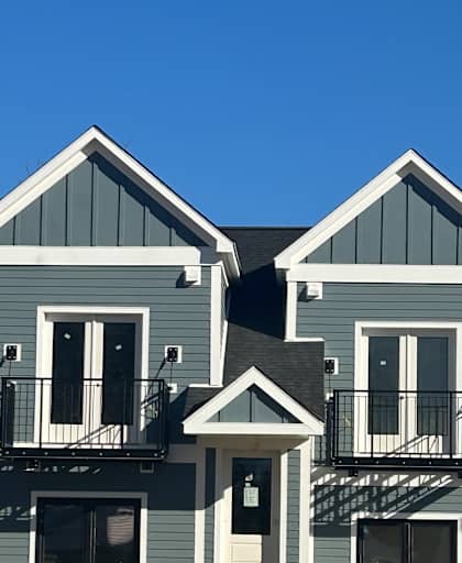 A building with a grey and white exterior is seen from a low angle.