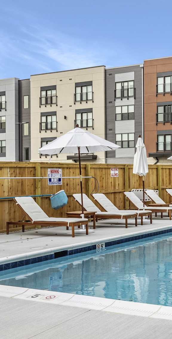 A large swimming pool surrounded by lounge chairs and umbrellas.