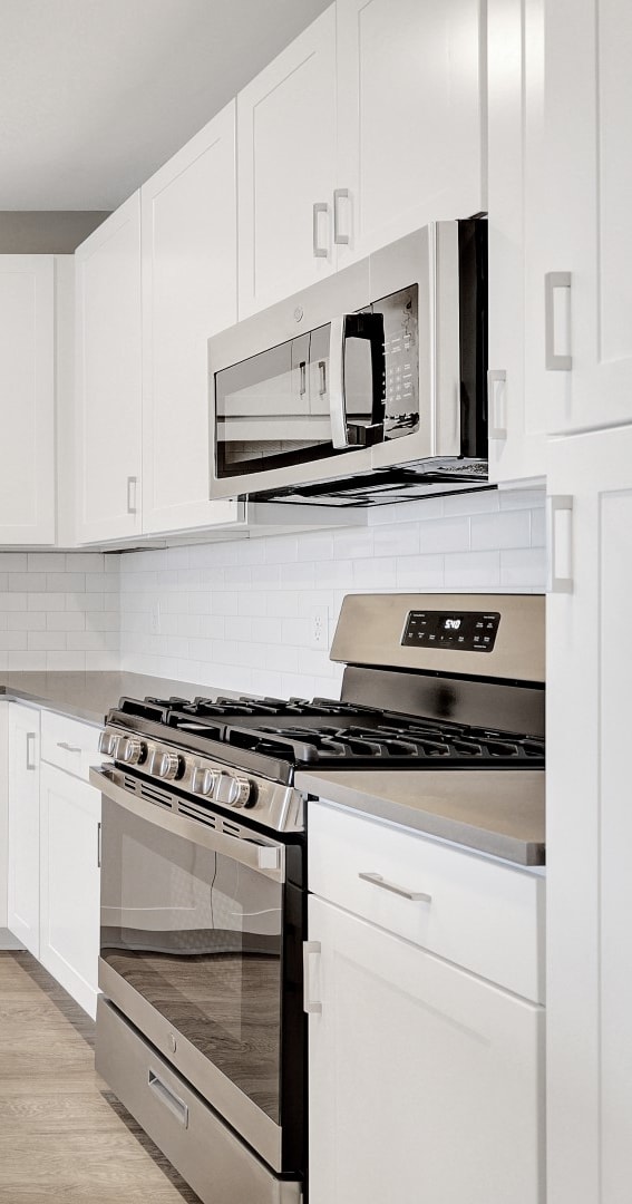 an all white kitchen with stainless steel appliances and white cabinets