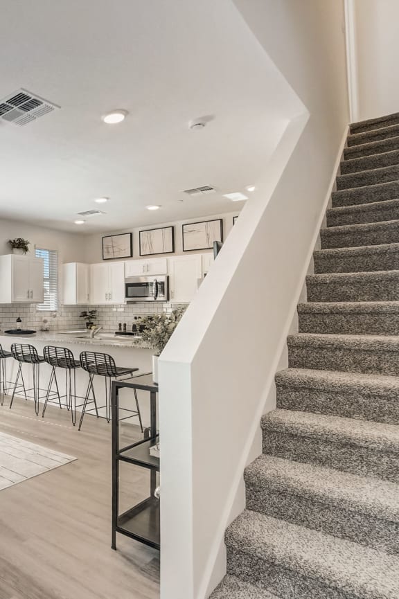 a living room with a staircase and a kitchen in the background