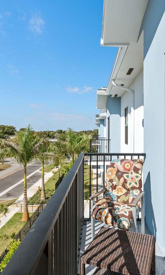A balcony with a view of a street and palm trees.