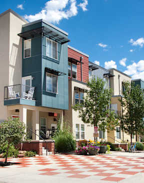 A modern building with a green and white facade is surrounded by a courtyard with a red and white checkered floor.