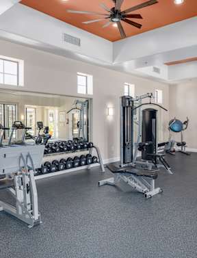 a spacious fitness room with cardio equipment and weights