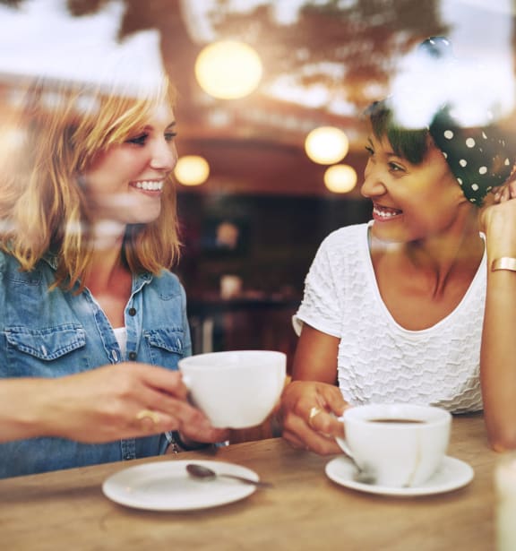 two women sitting at a table drinking coffee