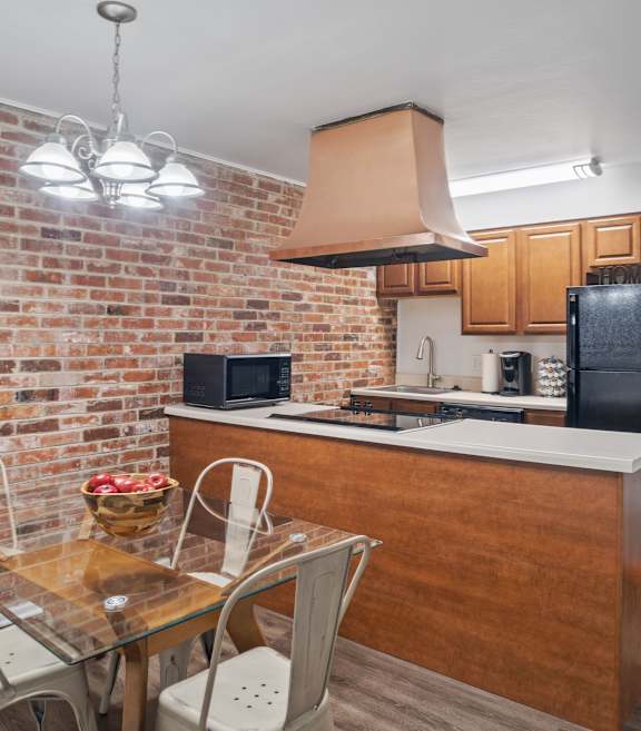 A kitchen with a brick wall and a wooden counter.