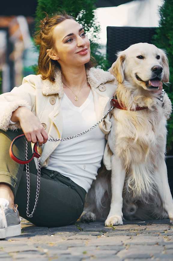 A woman is sitting on the ground with her dog. at The Sully, Chantilly