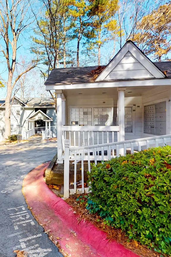 A white house with a porch and a red stripe on the side of the road.