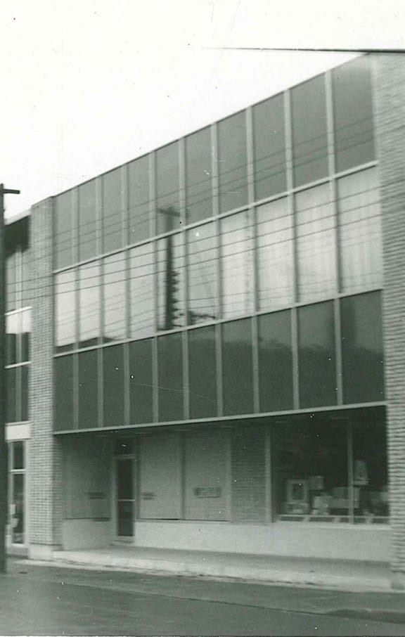 A black and white photo of a building with a large glass window.