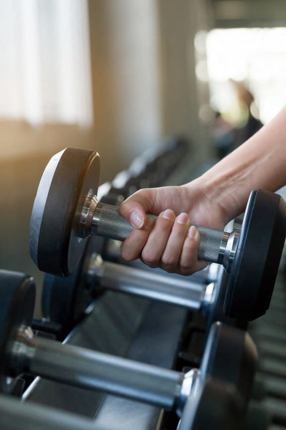 a woman lifting dumbbells on a treadmill in a gym  at SoRoc On Maine, Rochester, MN