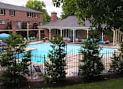 Thumbnail 9 of 26 - A pool surrounded by trees and a building in the background.