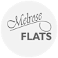 A white circle with the words "Melrose Flats" written in black.