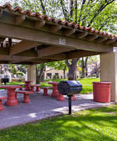A covered picnic area with red benches and a barbeque