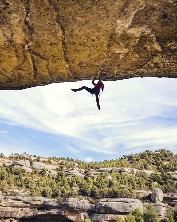 a climber dangling from a rock over a canyon