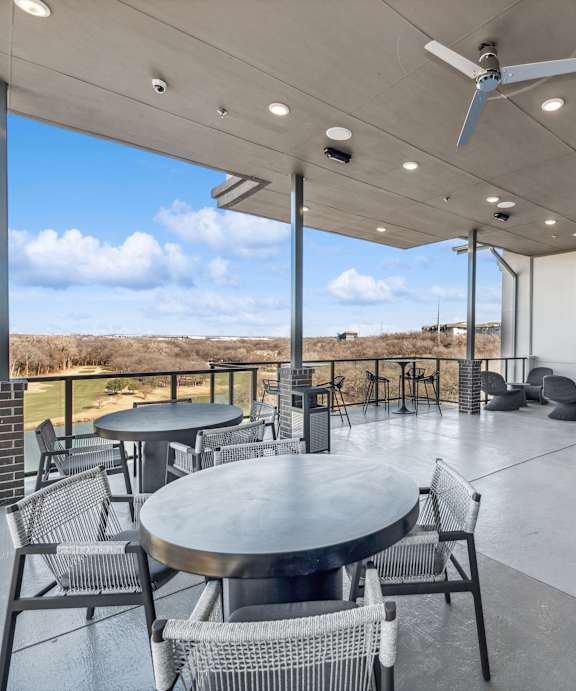 A patio with a table and chairs overlooking a body of water.
