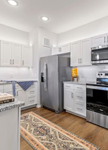 a kitchen with white cabinets and stainless steel appliancesat Mariposa at Harris Road Arlington 55+ Apartments, Texas