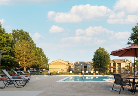 A sparkling outdoor pool at the clubhouse, with clear blue water, sun loungers, and umbrellas, invites residents to relax, swim, and enjoy leisurely moments in a beautiful, serene setting.