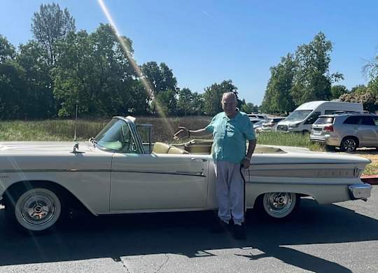 A man stands beside a white vintage car at River Commons Senior Living, Redding