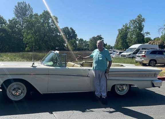 A man stands beside a white vintage car at River Commons Senior Living, Redding