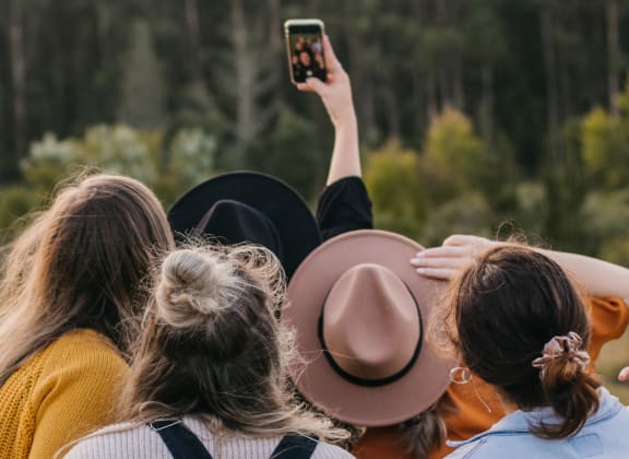 three women are looking at a cell phone