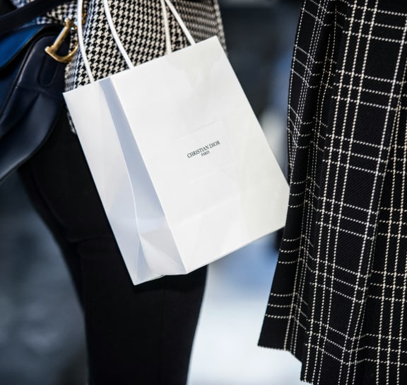 two women are holding white bags on their legs