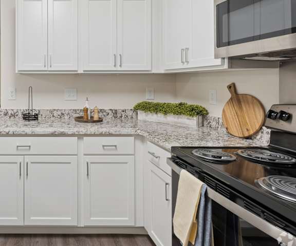 A kitchen with white cabinets and granite countertops.