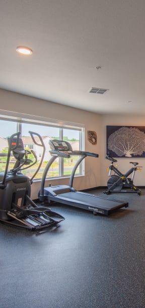 a gym with exercise equipment on the floor and a window