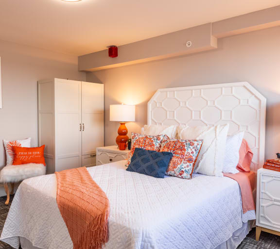 a bedroom with a white bed and orange pillows