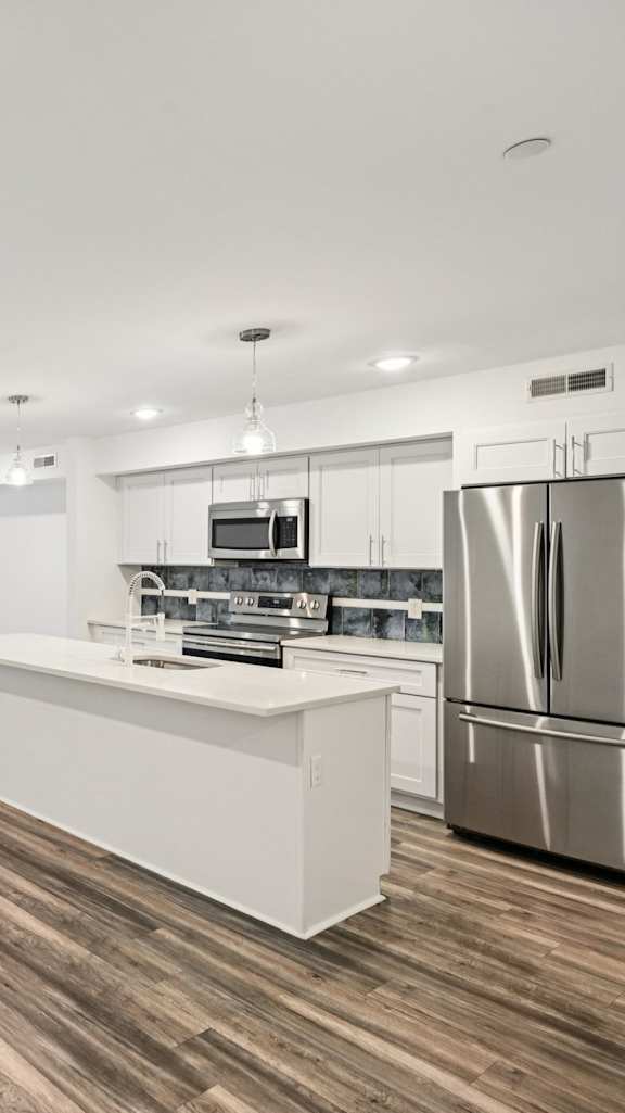 A kitchen with a white island and stainless steel appliances.