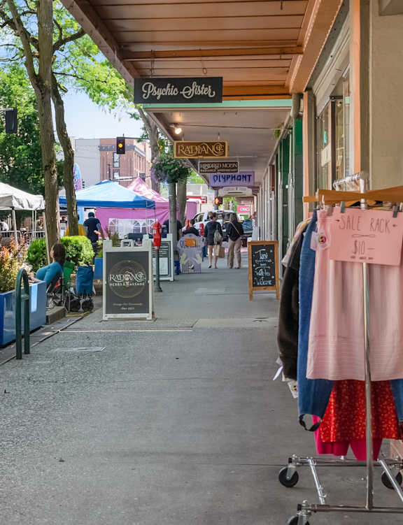 A street view of a shopping area with clothes on display.