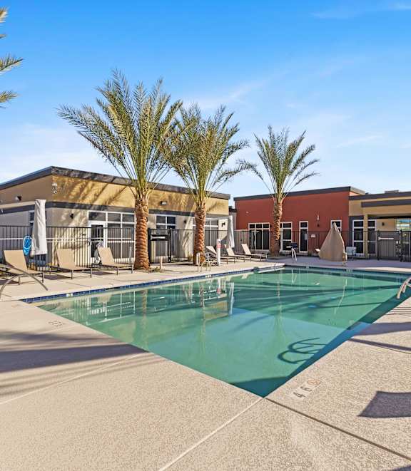 A pool surrounded by palm trees and sun loungers. at Agave House Apartments, Casa Grande, 85122