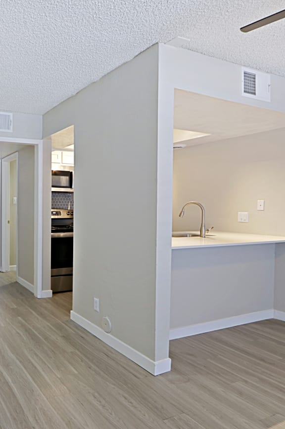 a bedroom with a desk and a kitchen in the background