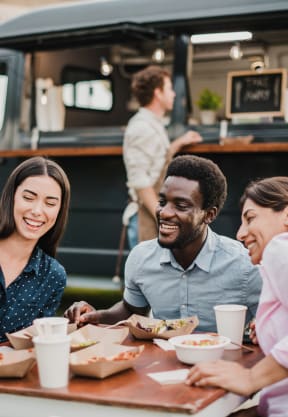 a group of people sitting at a table in front of a food truck