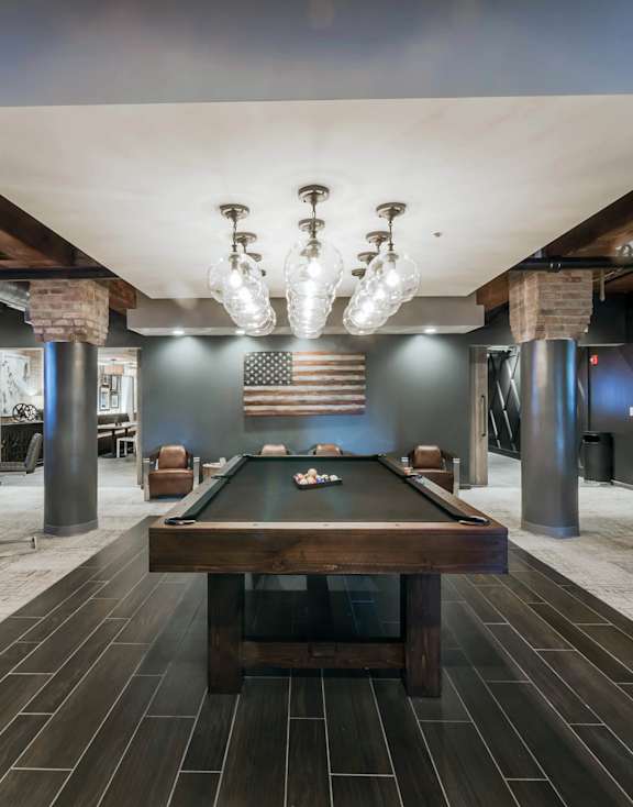 A room with a pool table and a bar area.