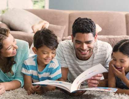 a family reading a book to his children in the living room