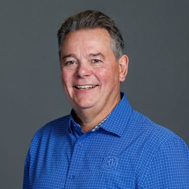 a man in a blue shirt smiles at the camera