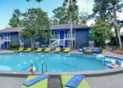 Thumbnail 12 of 23 - Mandarin Bay apartments with pool with lime green loungers and large patio couches with blue and teal cushions.