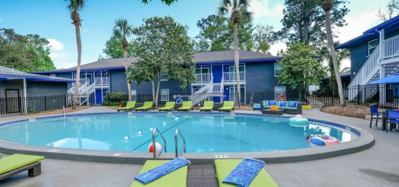 Mandarin Bay apartments with pool with lime green loungers and large patio couches with blue and teal cushions.