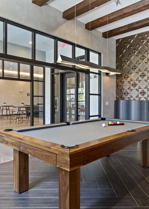 A pool table in a room with a wooden floor and a stone wall.