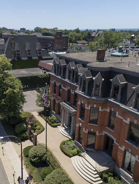 A street view of a city with a red brick building on the right. at The Knights @ 506 Delaware Apartments, Buffalo, 14202