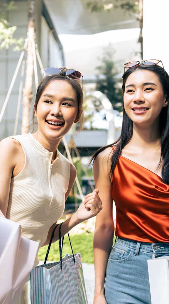Two women holding shopping bags in front of a building.